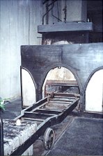 View of an oven with wheeled carts leading into the opening