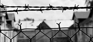 View into prison camp through a barbed wire fence